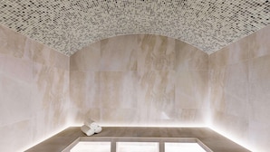 A minimalist bathroom with a large bathtub, a bench, and a tiled ceiling.
