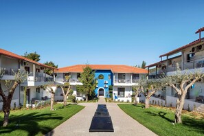 A courtyard with a central pathway leading to a building with a blue facade and red-tiled roof. - Philoxenia Hotel (Polygyros)