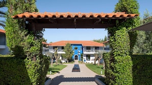A hotel entrance with a tiled roof, a central archway, and a pathway leading to the building.
