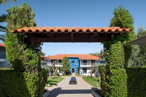 A hotel entrance with a tiled roof, a central archway, and a pathway leading to the building. - Philoxenia Hotel (Polygyros)