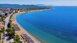Un pueblo costero con playa, mar azul cristalino y una carretera que lleva a la playa.