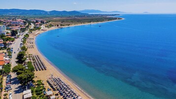Un pueblo costero con playa, mar azul cristalino y una carretera que lleva a la playa.