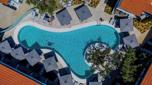 An aerial view of a swimming pool with lounge chairs and umbrellas, surrounded by a landscaped area and buildings. - Philoxenia Hotel (Polygyros)