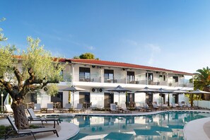 Un hotel con piscina, sillones de descanso y sombrillas.