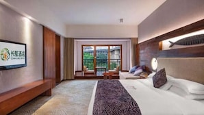 A hotel room with a bed, a television, a sofa, and a balcony with outdoor furniture. - Chimelong Hotel (Guangzhou)