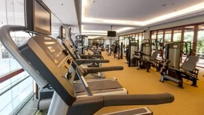 A gym with treadmills, weight machines, and a TV screen. - Chimelong Hotel (Guangzhou)