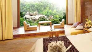 A room with a bed, two sofas, a small table, and a view of a natural landscape with rocks and greenery. - Chimelong Hotel (Guangzhou)