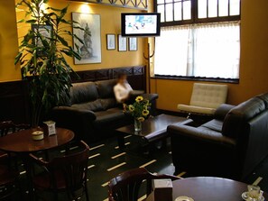 A cozy room with a sofa, armchair, and a dining table. There is a television mounted on the wall and a large window with curtains. - Hotel Ciudad De Calahorra (Calahorra)