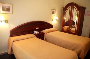 A hotel room with two single beds, a wooden headboard, bedside lamps, a telephone, and a mirror. - Hotel Ciudad De Calahorra (Calahorra)