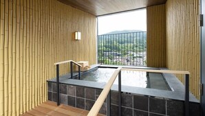Un espace de bien-être avec un jacuzzi, des murs en bois et une vue sur un paysage montagneux.
