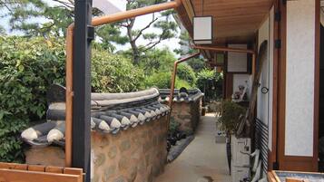A traditional Korean gate with a wooden structure and stone wall, leading to a pathway.