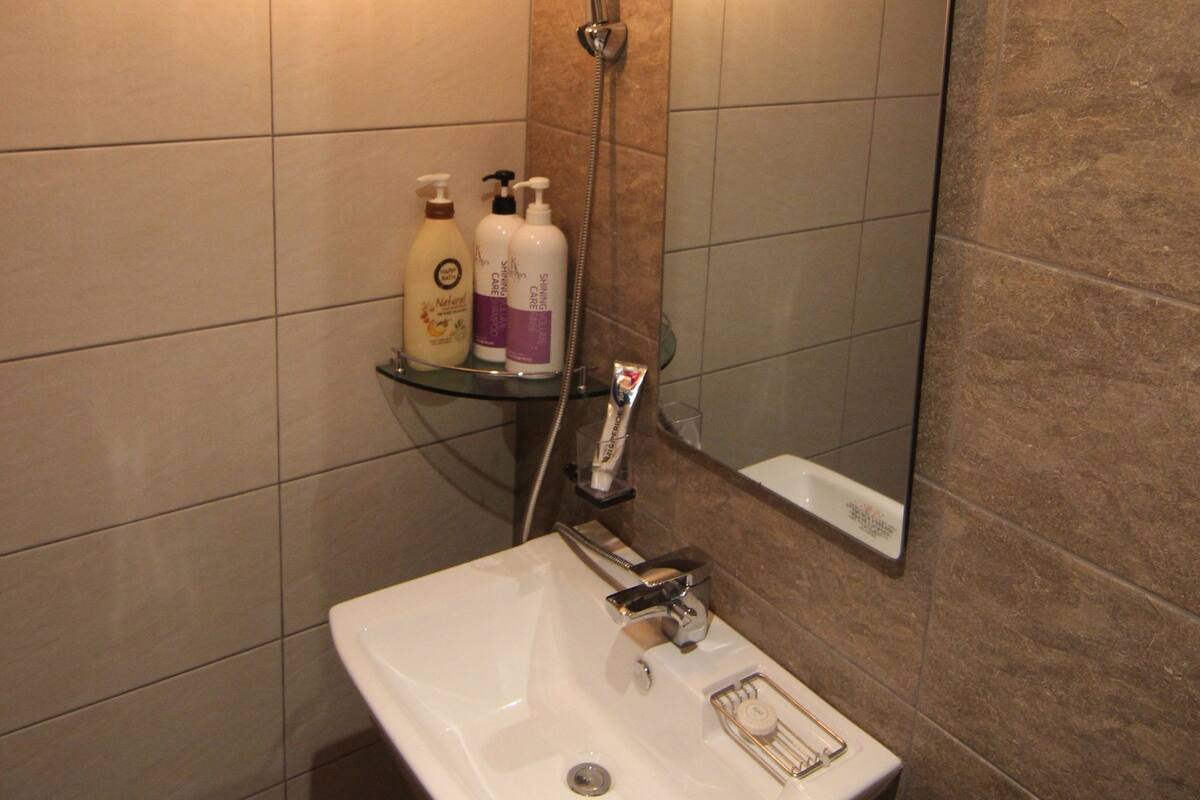 Une salle de bain avec un lavabo blanc, un miroir et deux luminaires.