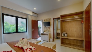 A hotel room with a bed, a desk, a TV, and a wardrobe.