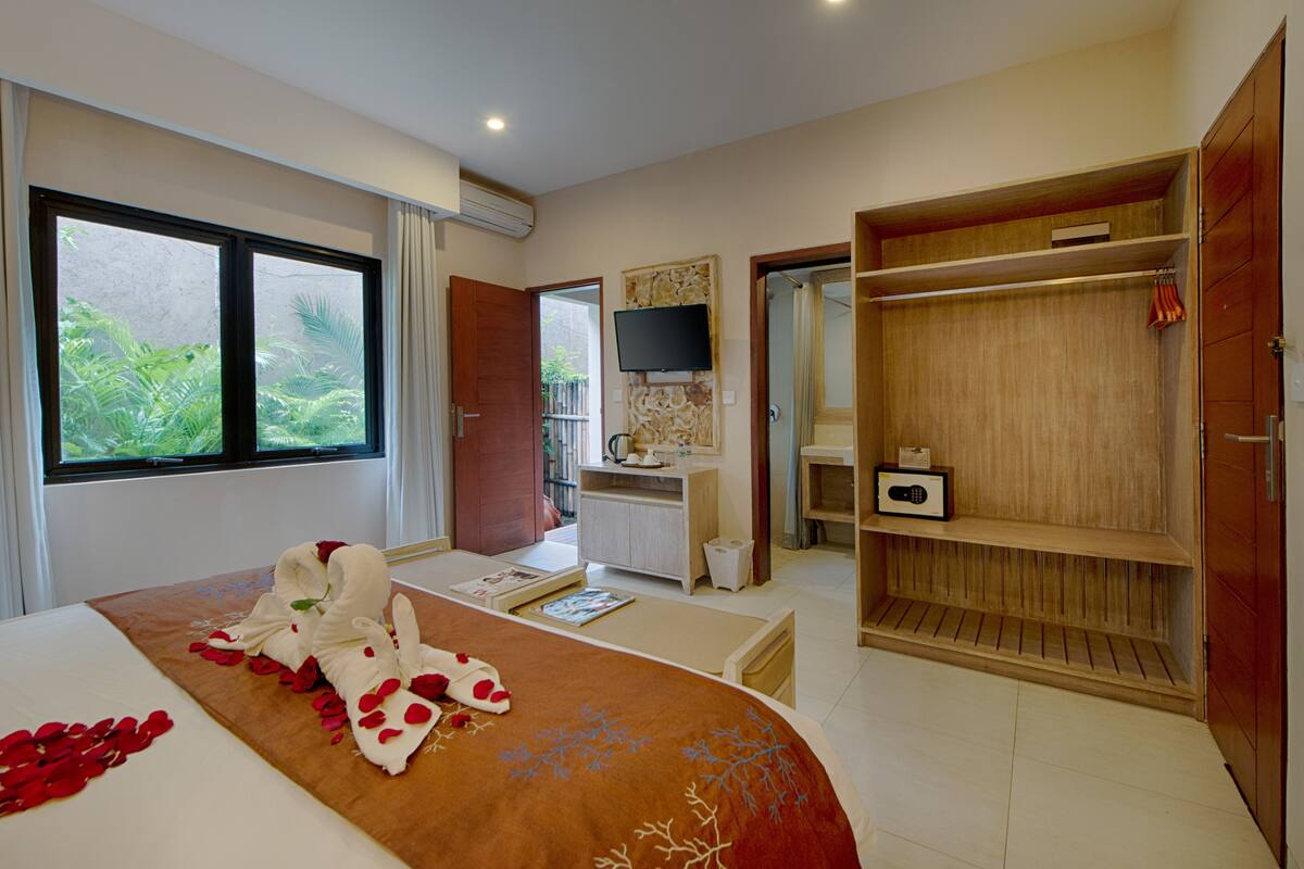A hotel room with a bed, a desk, a TV, and a wardrobe.