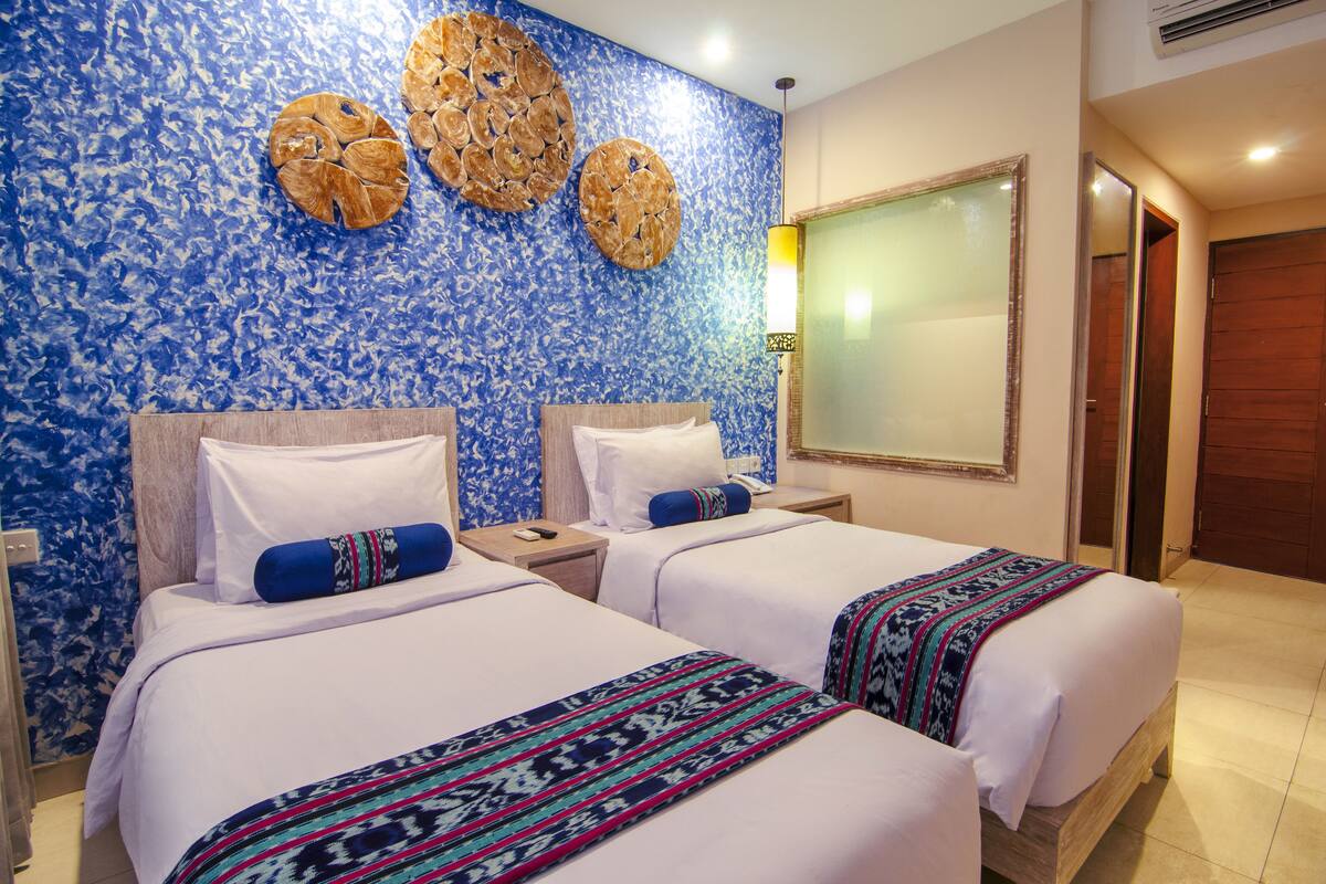 A hotel room with two beds, a large mirror, and a decorative wall.