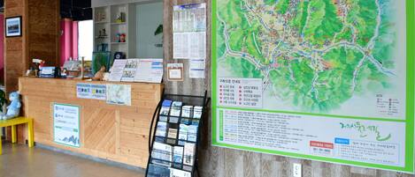 A reception area with a wooden reception desk, a map, and informational posters.