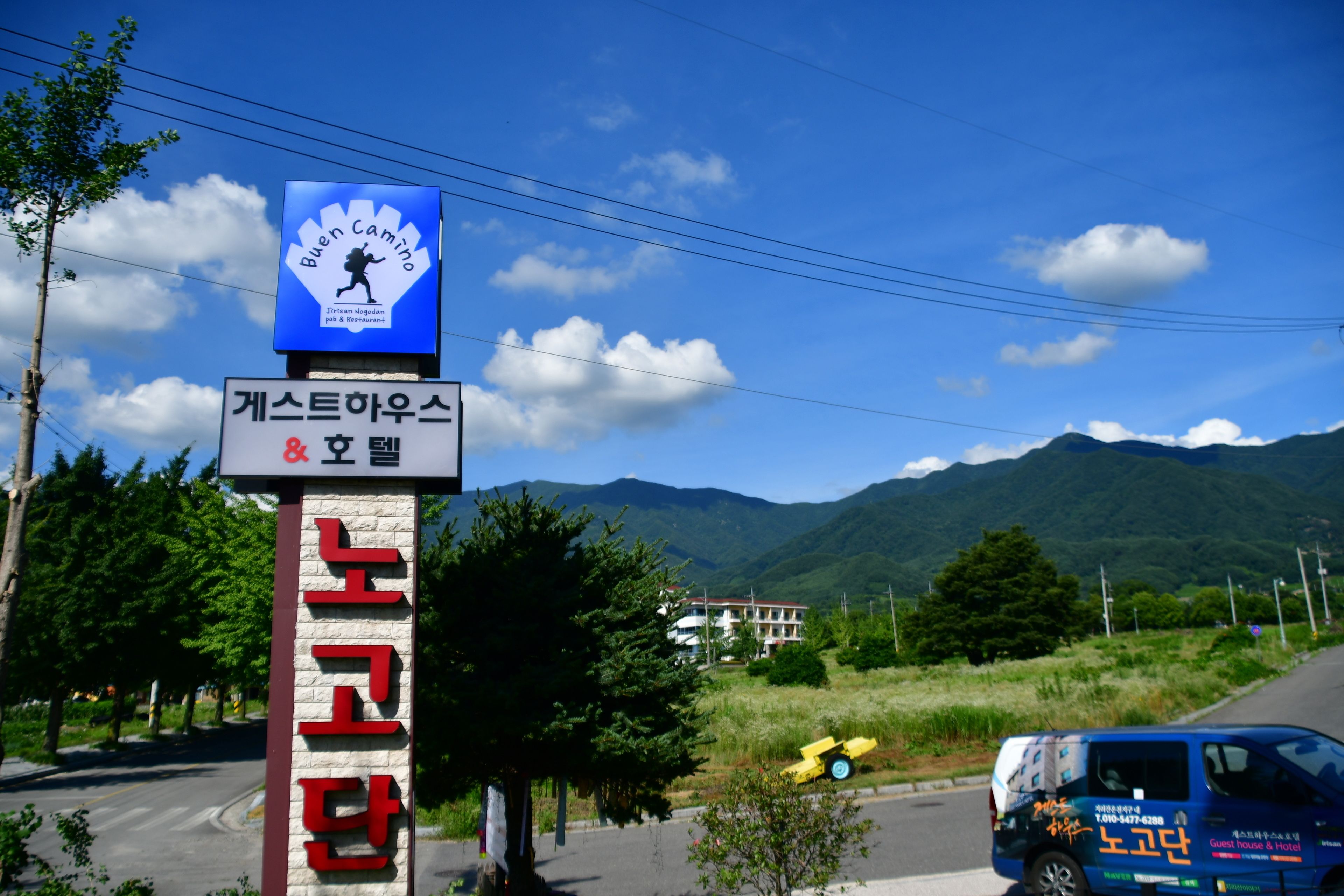 A sign for a guest house and hotel with a mountain backdrop.