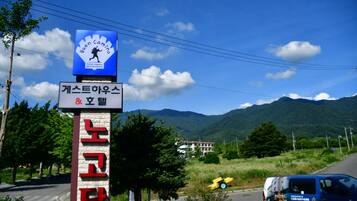 A sign for a guest house and hotel with a mountain backdrop.