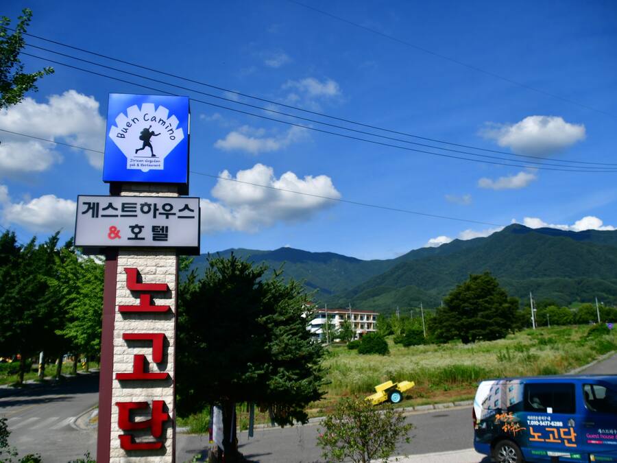 A sign for a guest house and hotel with a mountain backdrop.