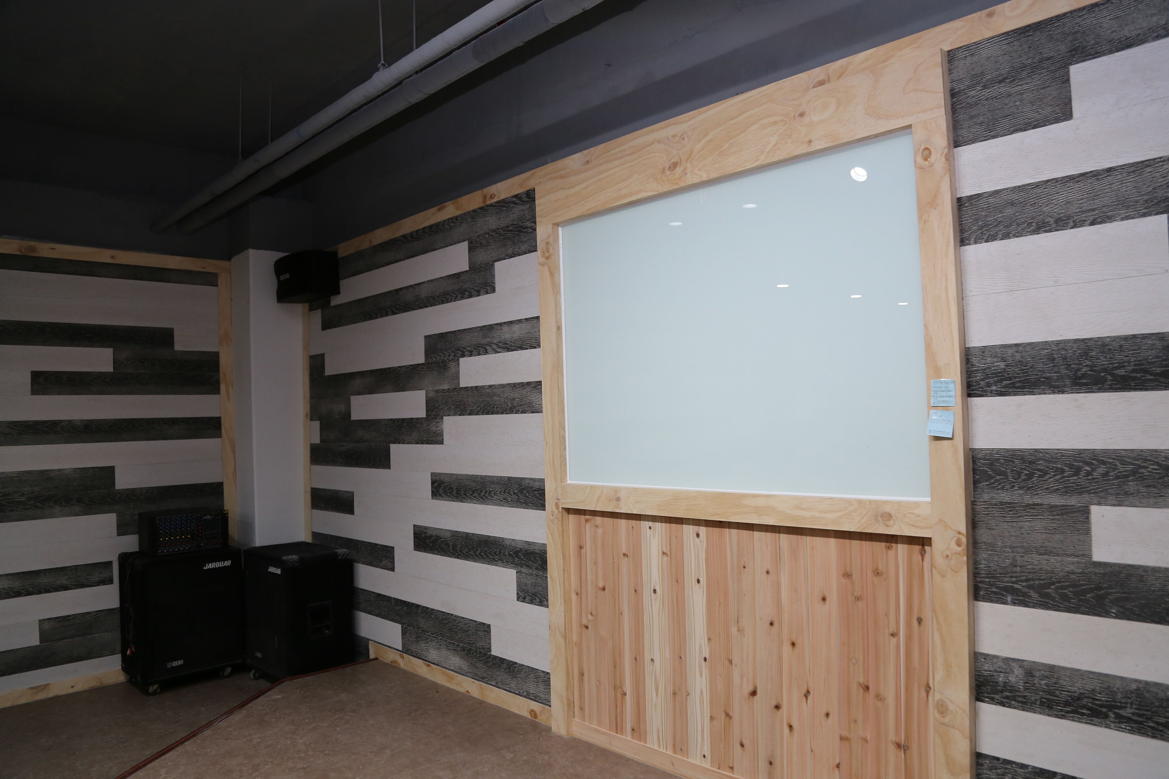 A conference room with a whiteboard, black and white patterned walls, and two black speakers.