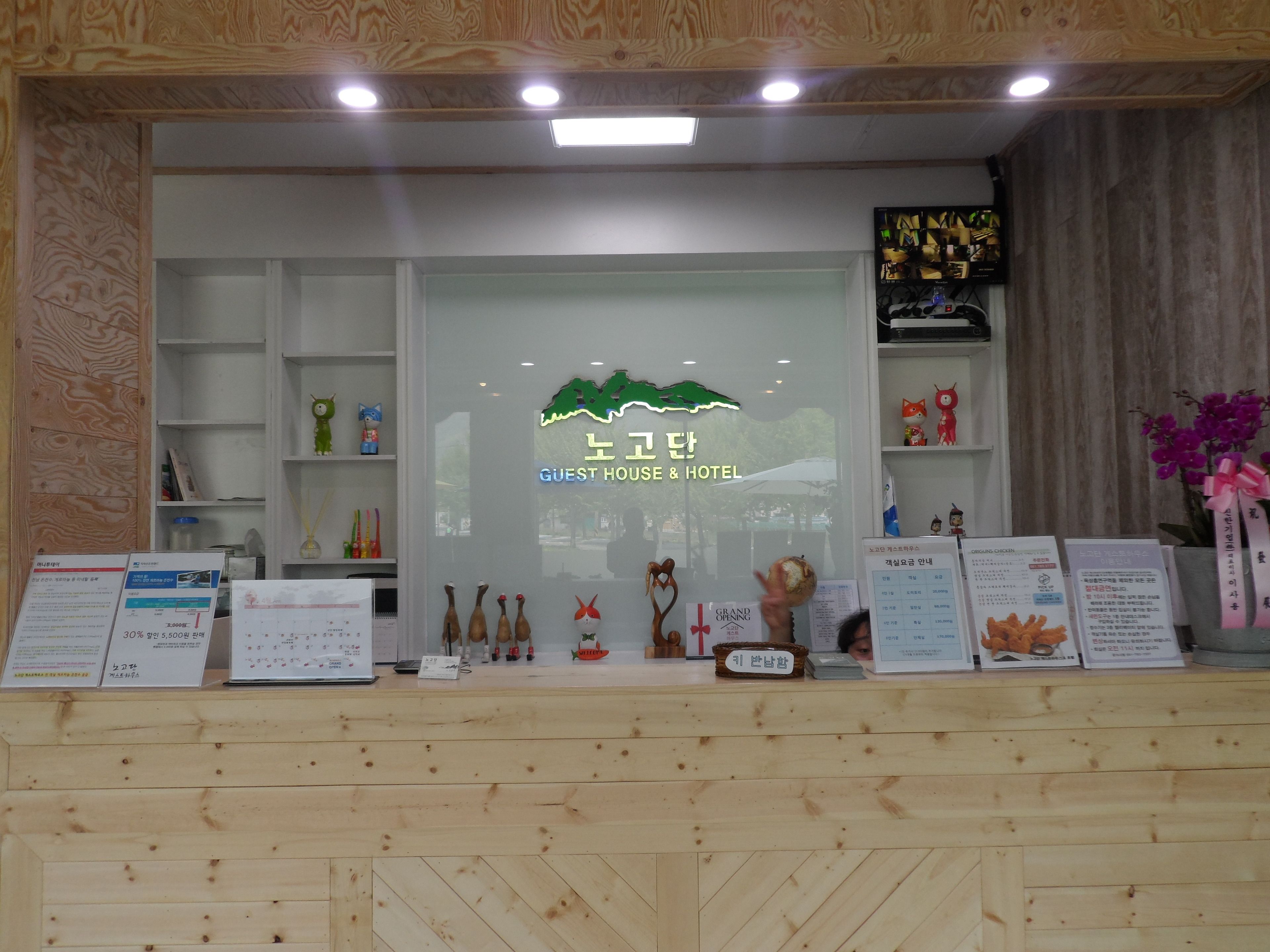 A reception desk with a sign reading "GUEST HOUSE & HOTEL" and various informational brochures.