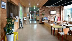 Un interior moderno con techo de madera, paredes de ladrillo y una zona de recepción con mostrador y sillas.