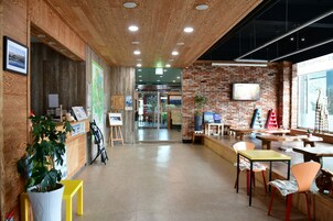 Un interior moderno con techo de madera, paredes de ladrillo y una zona de recepción con mostrador y sillas.