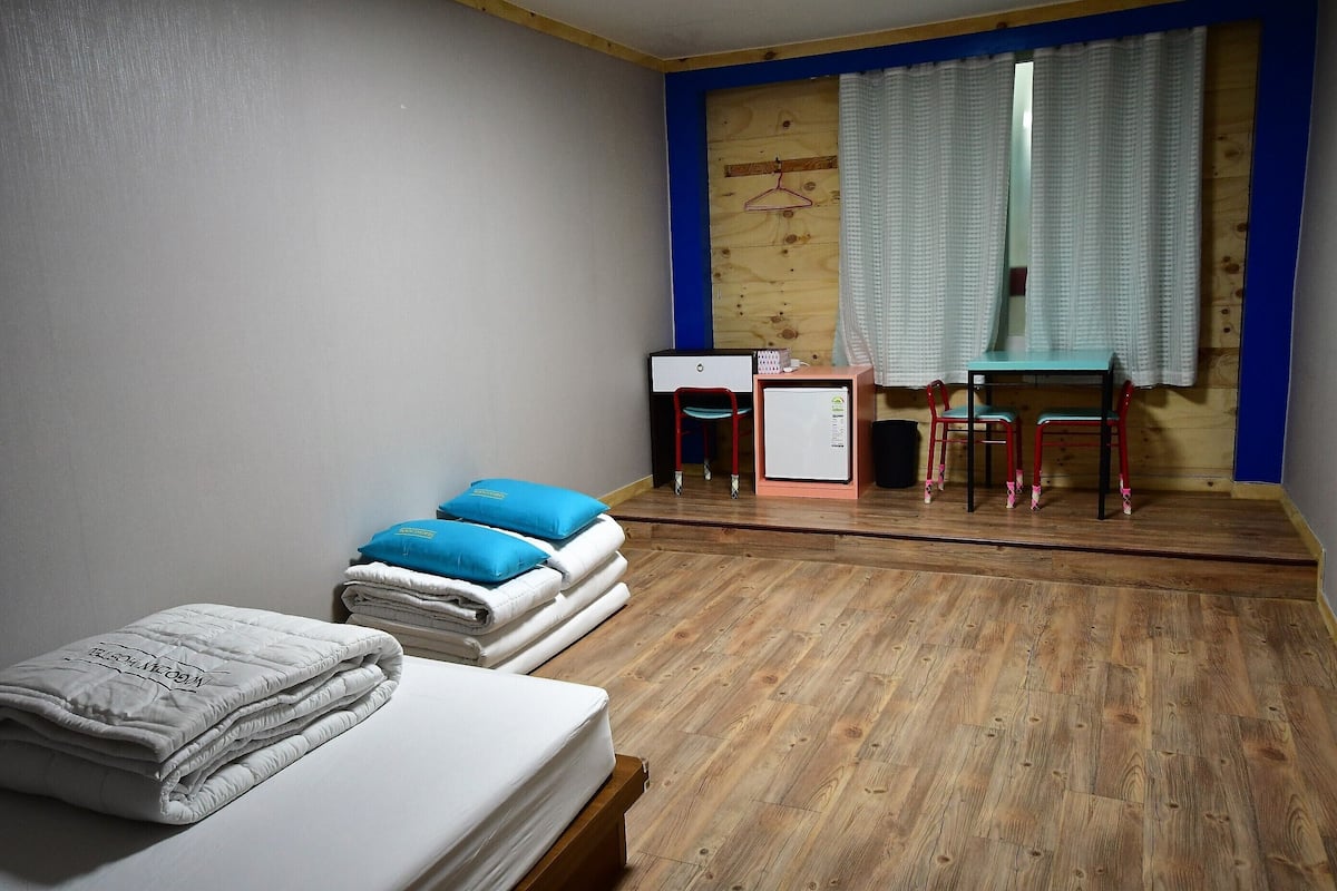 Ein Schlafzimmer mit Bett, Schreibtisch, Stuhl und kleinem Tisch.