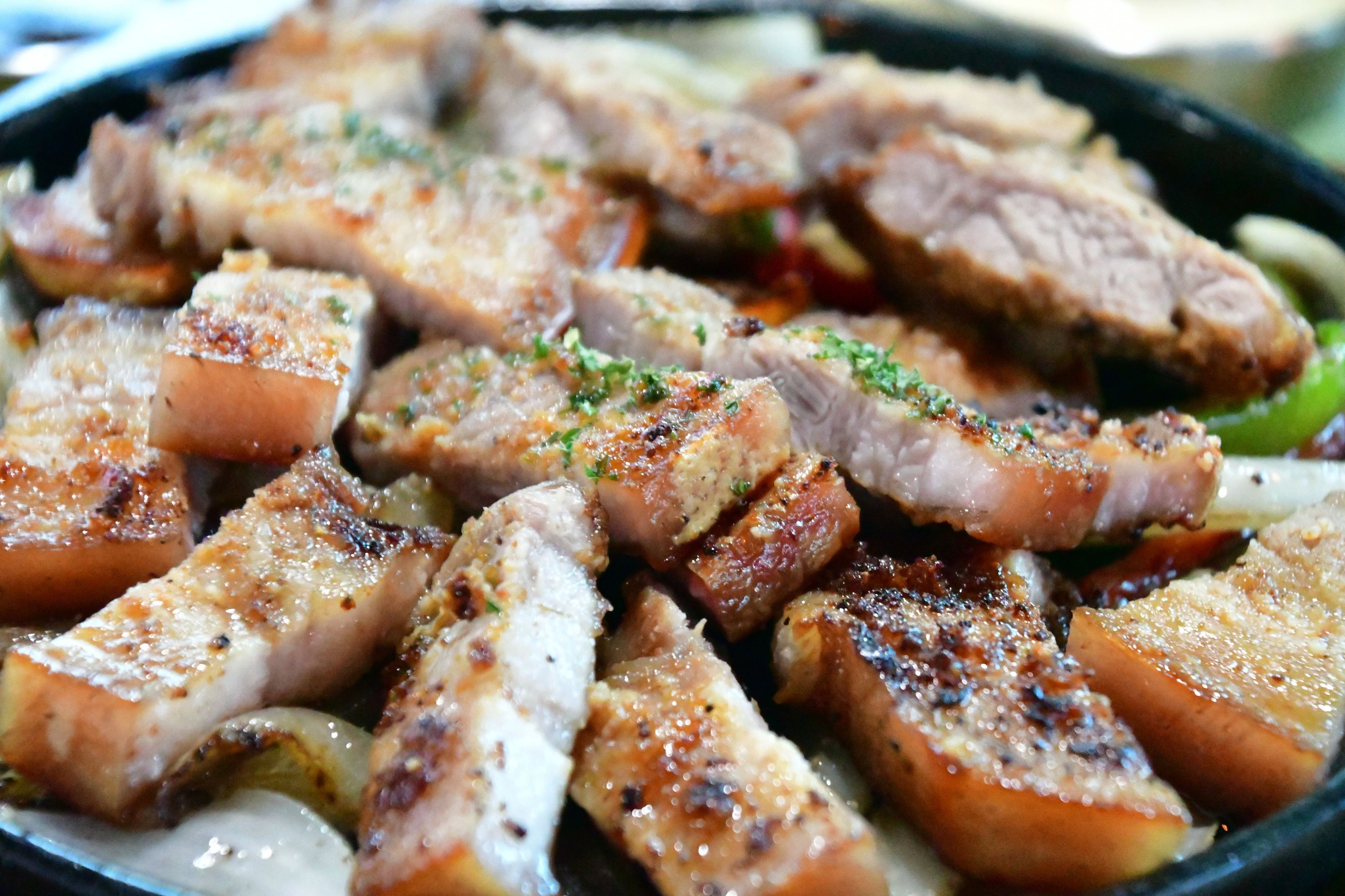 A close-up of cooked pork belly with visible seasoning and herbs.