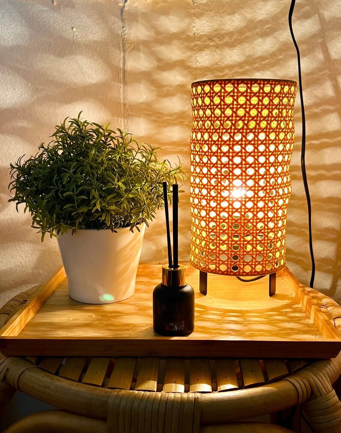 A potted plant, a candle holder, and a decorative lamp on a wooden tray.