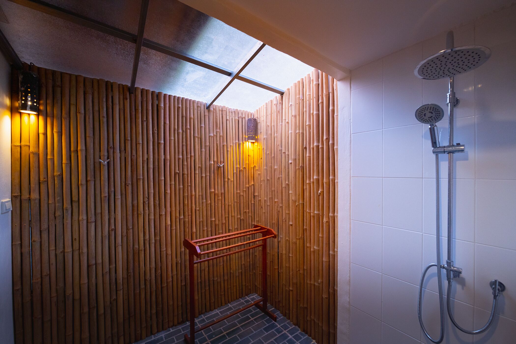 A modern shower area with a bamboo wall, a glass ceiling, and a handheld showerhead.