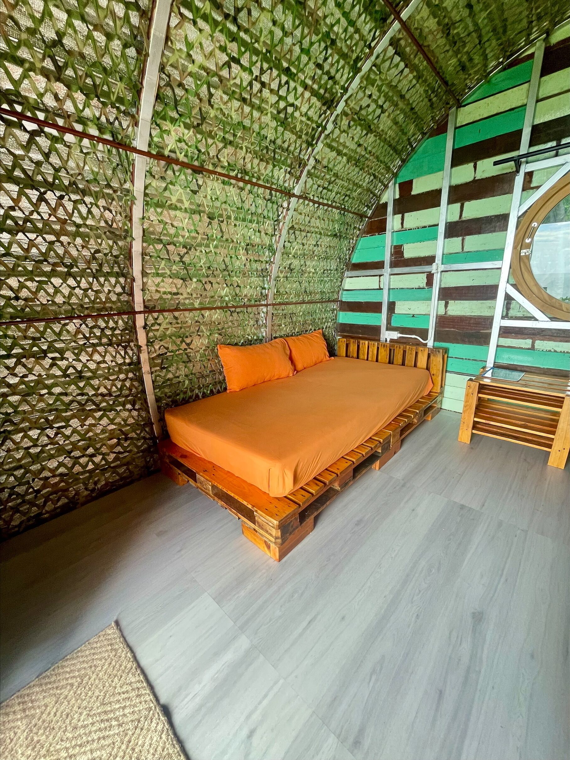 A room with a bed, a window, and a wall with a green and white pattern.