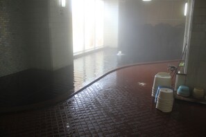 A wet tiled floor with a steam shower, a water dispenser, and a tiled wall with a window. - Hot Spring Hotel Boston (Obihiro)
