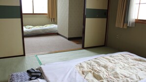A traditional Japanese-style room with tatami flooring, a futon bed, and sliding doors. - Hot Spring Hotel Boston (Obihiro)
