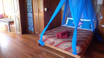 A wooden room with a bed under a blue canopy, a wooden bench, and a patterned curtain.