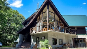 A modern building with a large glass balcony, a visible sign reading "Pension," and a green roof. - Pension Gooseberry (Furano)