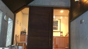 A wooden door leading into a room with a tiled floor and a visible kitchen area. - Pension Gooseberry (Furano)