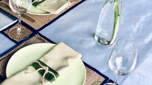 A table set with a green leaf centerpiece, clear glassware, and woven placemats. - Sabaidee House (Sukhothai)