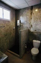 Un baño con cabina de ducha, inodoro y ventana.