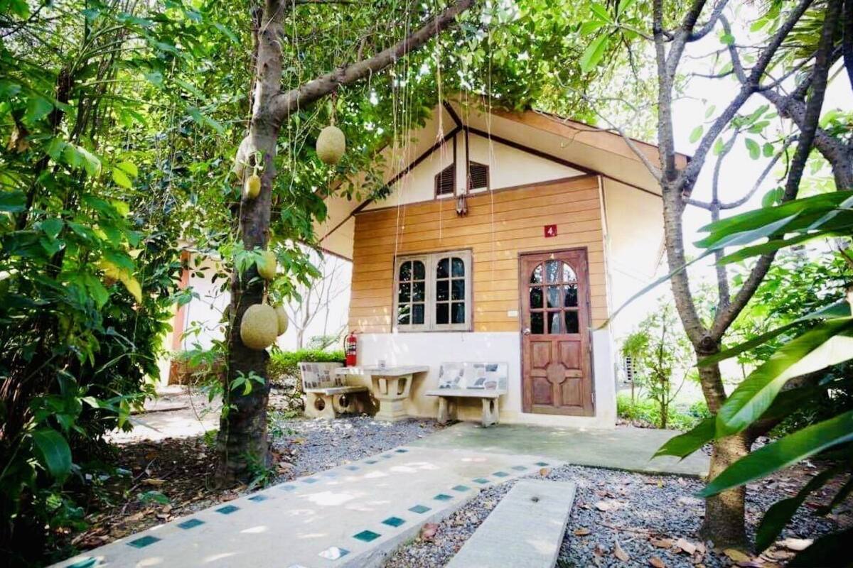 A small wooden building with a tiled entrance, surrounded by lush greenery and trees.