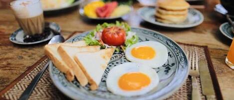 A dining table with plates of food, including eggs and toast, and a cup of coffee.