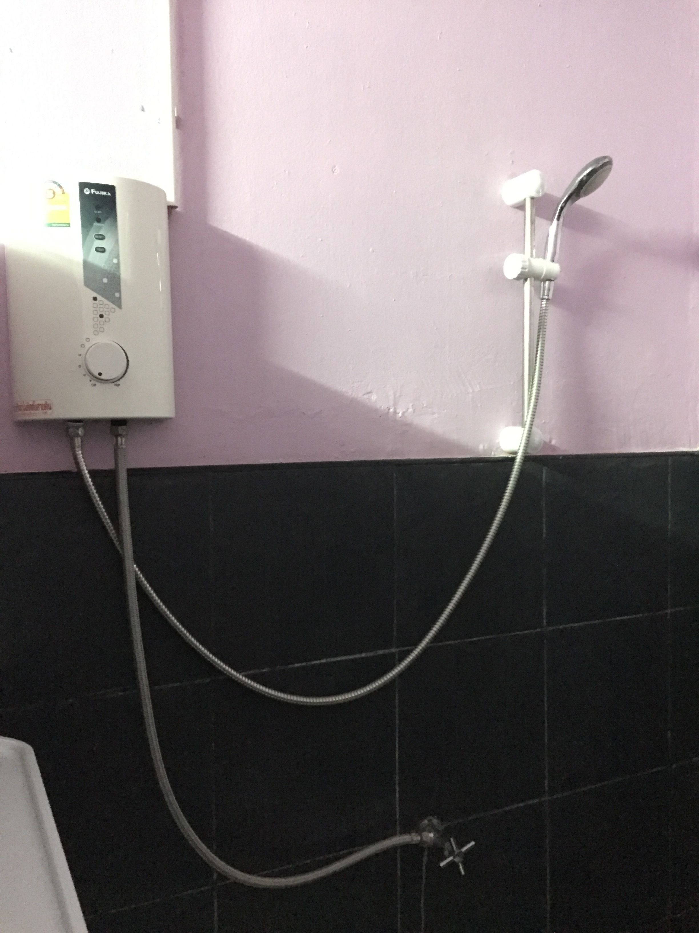 A bathroom with a white wall-mounted heater, a shower head, and a handheld shower attachment.