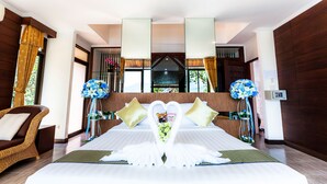 A hotel room with a large bed, a wicker chair, and a desk with a computer. - Chai Chet Resort Koh Chang (Ko Chang)