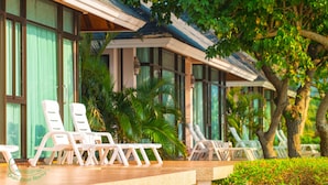 A resort with outdoor seating, palm trees, and a modern building with large windows. - Chai Chet Resort Koh Chang (Ko Chang)