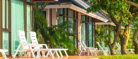 Un resort con mobiliario exterior, palmeras y un edificio moderno con amplios ventanales.