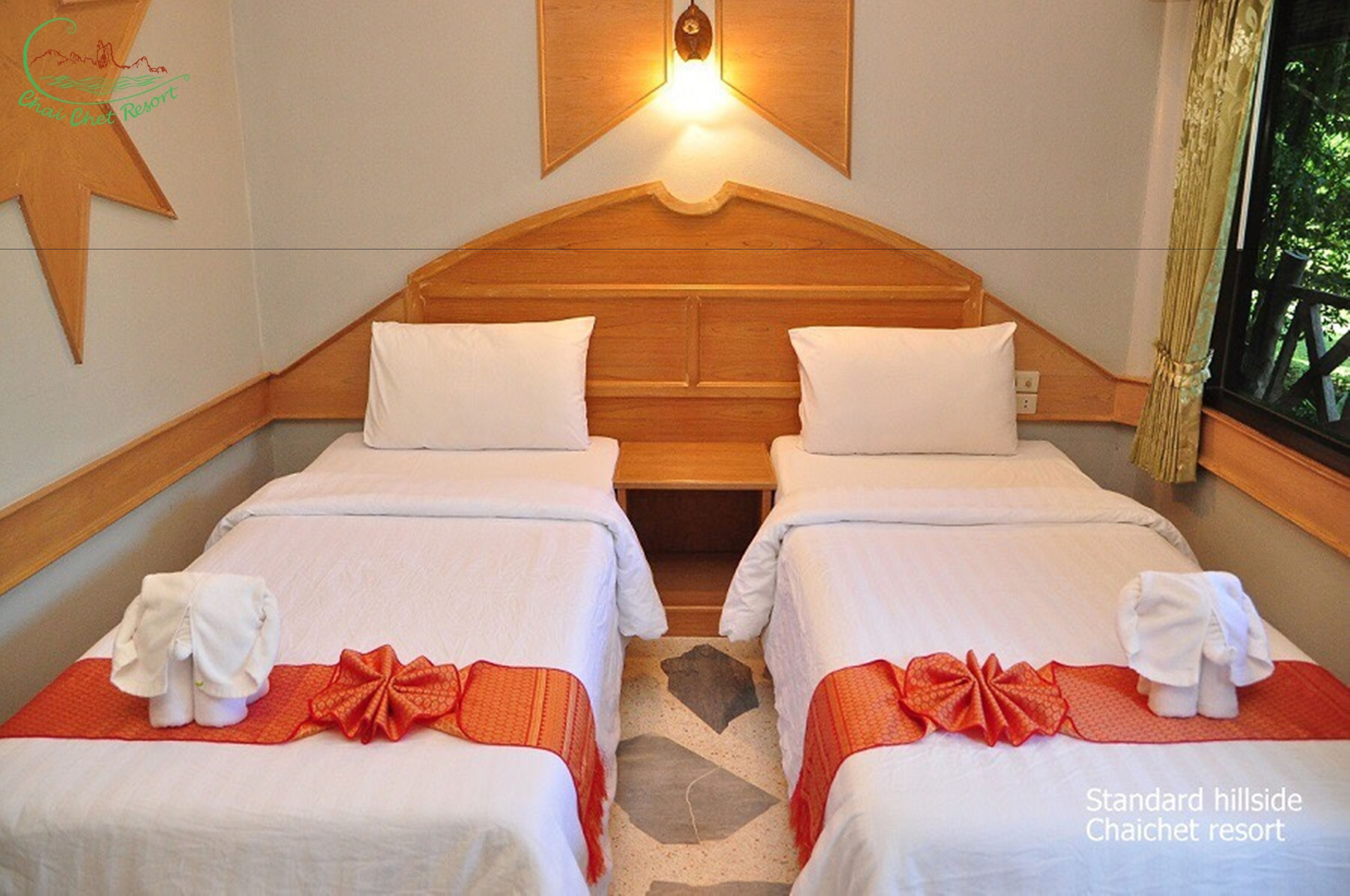 Habitación estándar en el resort Chaichet, ubicada en una ladera, con dos camas, cabecera de madera, luz nocturna y una decoración con forma de estrella en la pared.