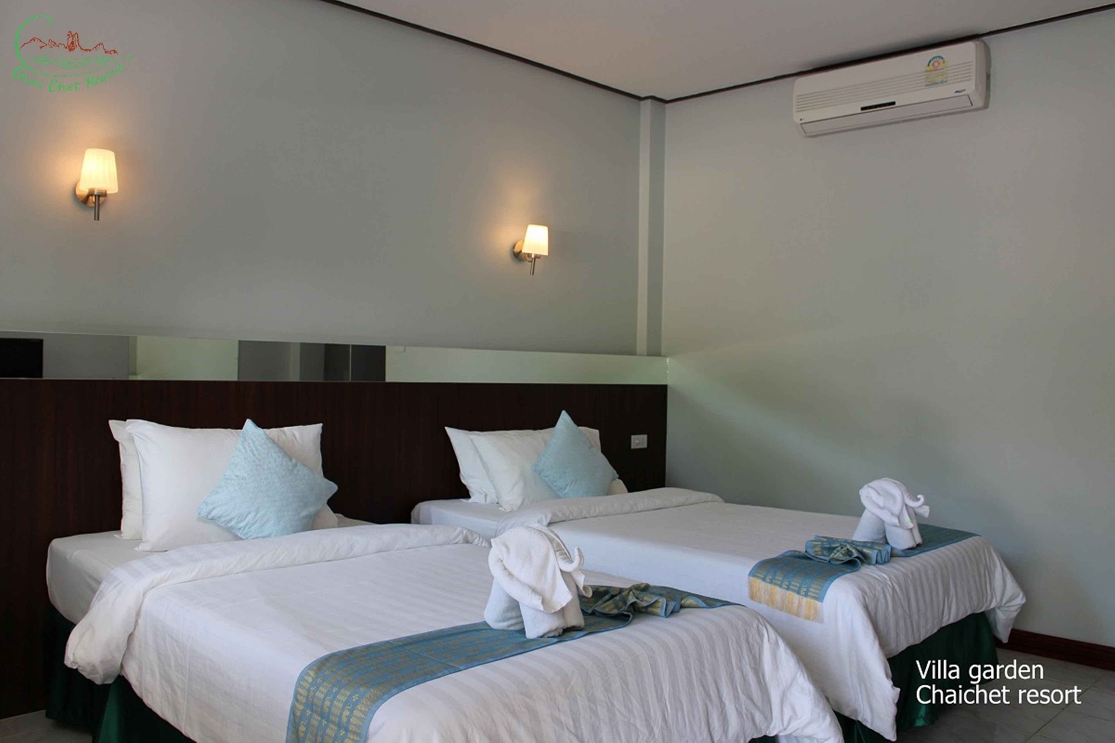 Een hotelkamer met twee bedden, een hoofdeinde, wandairconditioning en twee wandlampen.