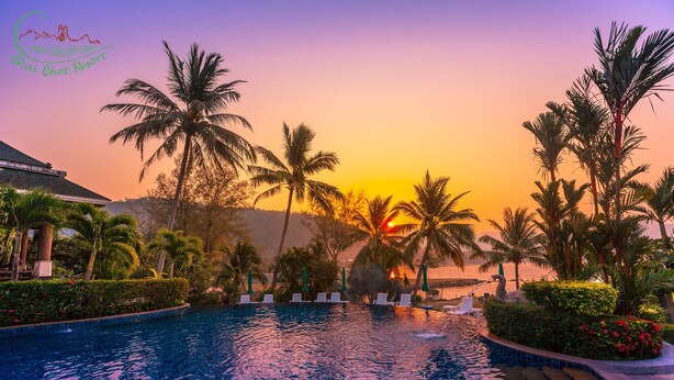 A resort pool with palm trees and a sunset view. - Chai Chet Resort Koh Chang (Ko Chang)