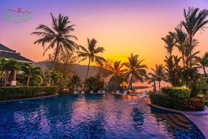 A resort pool with palm trees and a sunset view. - Chai Chet Resort Koh Chang (Ko Chang)