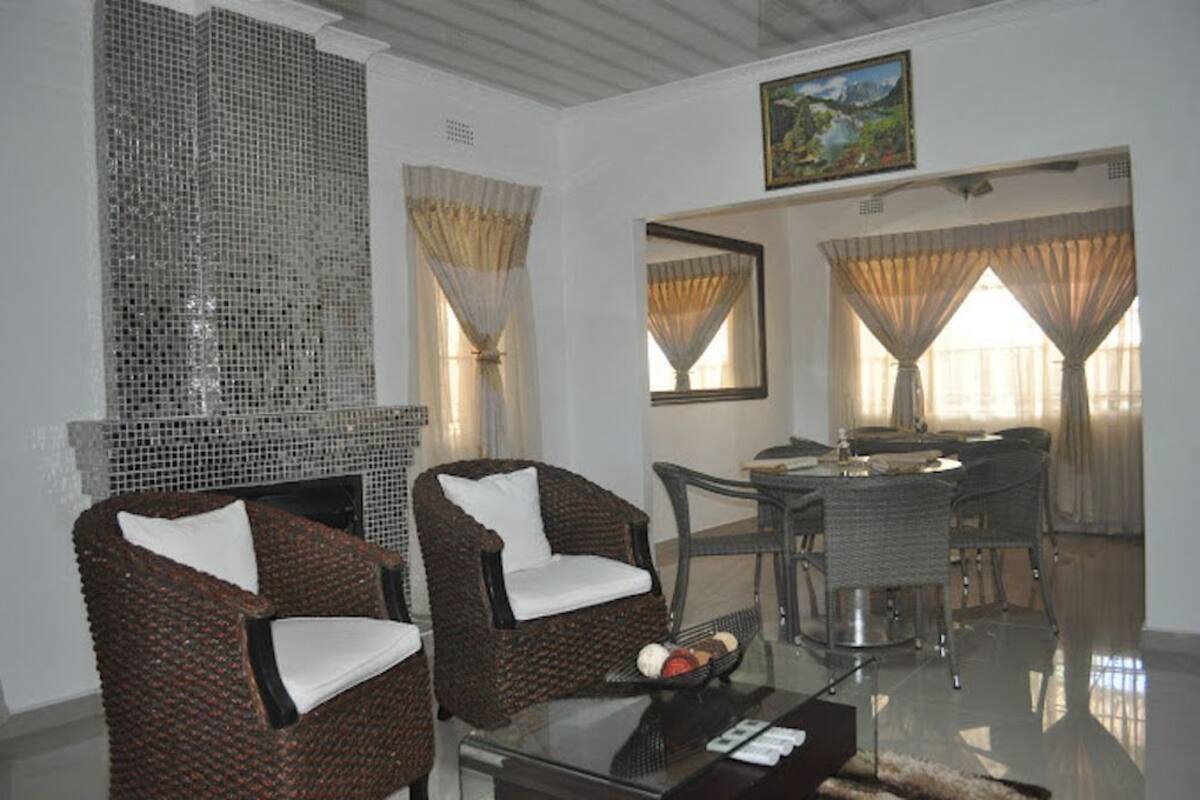 A living room with wicker chairs, a glass coffee table, and a dining area with a table and chairs.